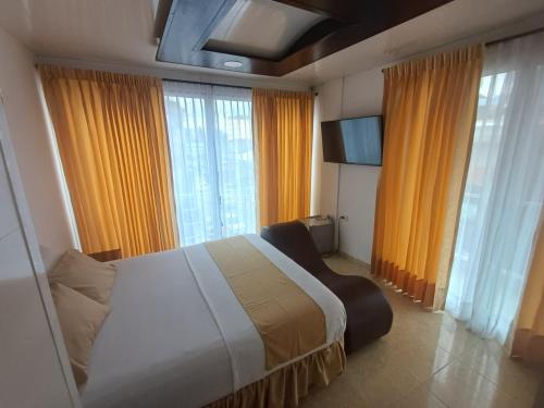 a bedroom with a large bed and windows with yellow curtains at HOTEL DULCES SUEÑOS in Buenaventura