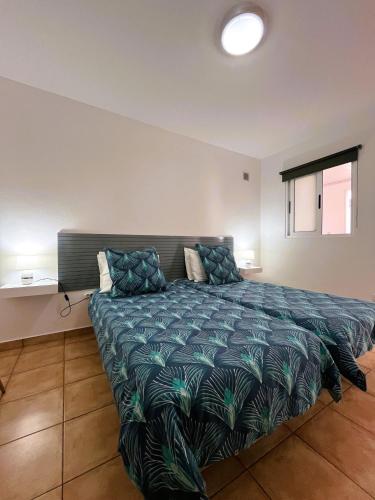 a bedroom with a large bed with a green comforter at Casa Pão - 5 mins from Machico centre with private parking in Machico