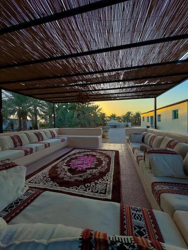 a covered patio with white couches and a rug at Palmas Resort in ‘Ayn al Fayḑah
