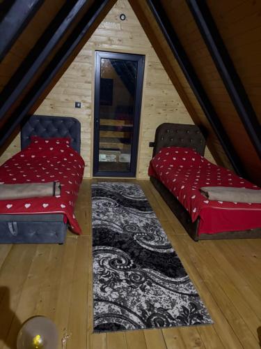 a attic room with two beds and a rug at ROMANIJA vikendice in Koprivice