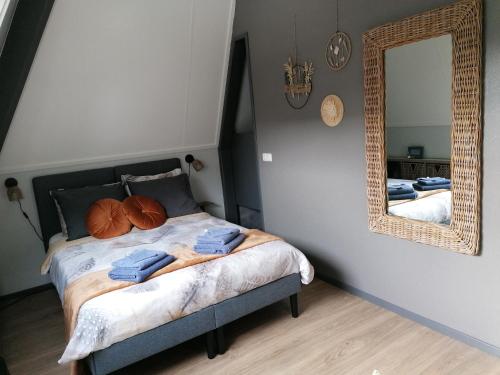 a bedroom with a bed with a mirror on the wall at Tusken Wad en Wâld in Kollumerzwaag