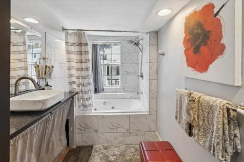 a bathroom with a tub and a sink and a window at Awesome Downtown Condo with Pool! in Savannah