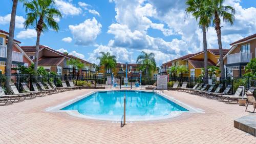 a swimming pool at a resort with chairs and palm trees at Enchanting Escape 3 Bedroom Minutes from Disney! in Kissimmee