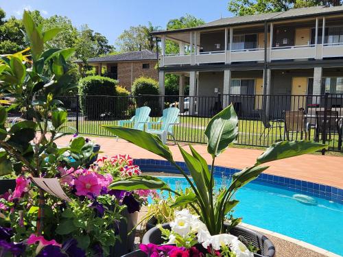 a house with a swimming pool and some flowers at Bucketts Way Motel Gloucester in Gloucester
