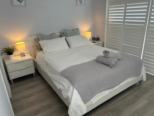 a bedroom with a large white bed with two lamps at Cozy guest suite in Margate, 200 mts from beach in Woody Point