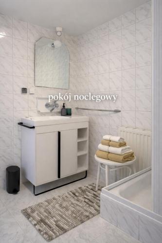 a white bathroom with a sink and a tub at Pokój noclegowy in Józefowo
