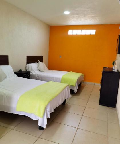 two beds in a hotel room with yellow walls at Villa Platino Doble in Pachuca de Soto