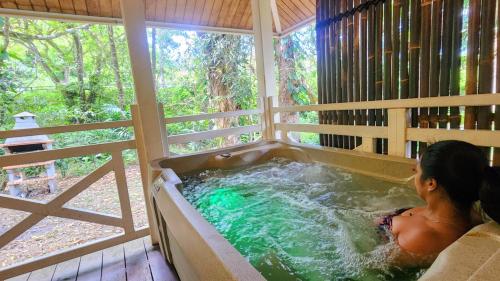a woman sitting in a hot tub in a house at EVASION Bungalow d'Antan Spa in Sarraméa