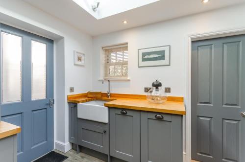 a kitchen with gray cabinets and a sink and a blue door at 2 Bed in Holt oc-p27287 in Holt