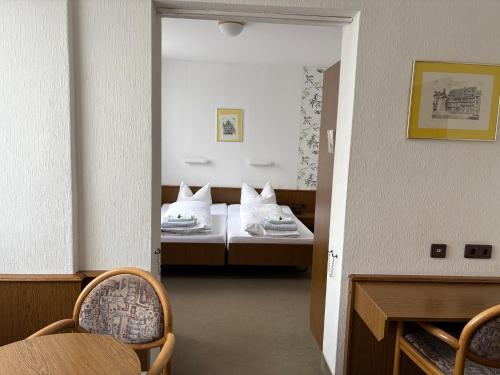 a room with two beds and a table and chairs at Lessinghof in Braunschweig