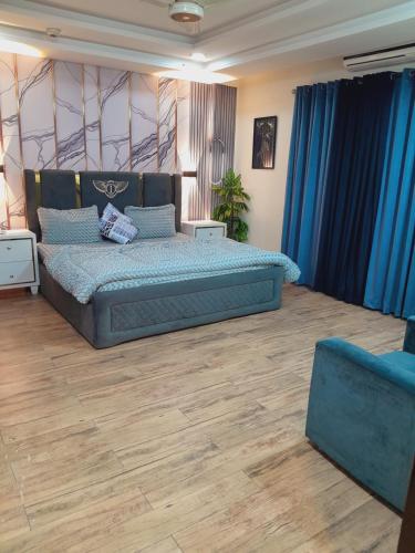 a bedroom with a large bed and blue curtains at Urban Pearl Apartment in Rawalpindi