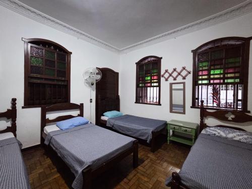 a room with three beds and two windows at Vila Mariah Hostel in Belo Horizonte