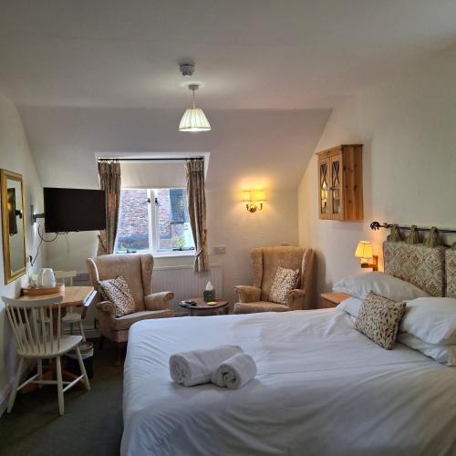 a hotel room with a bed and chairs and a table at The Abbey Hotel & Apartments in Bury Saint Edmunds