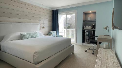 a bedroom with a bed and a desk and a window at The Colony Hotel Kennebunkport in Kennebunkport