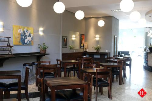 a restaurant with wooden tables and chairs and lights at Hotel Elevado in Porto Alegre