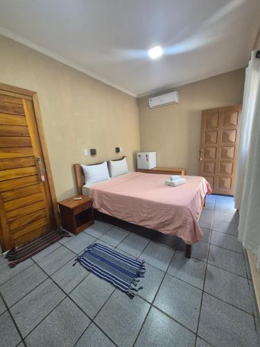 a bedroom with a bed with a pink bedspread at Pousada Costa do Sol in Canavieiras