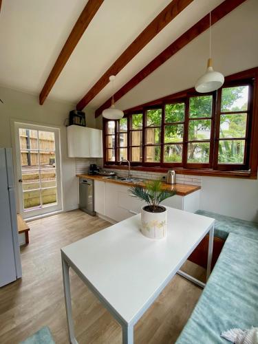 a kitchen with a white table with a potted plant on it at Kauri Coast Bungalow in Karekare