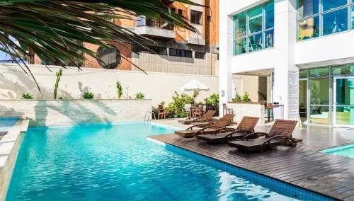 a swimming pool with chaise lounge chairs next to a building at Mandai Apart - Beira Mar in Cabo Frio
