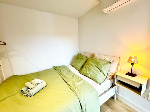 a small bedroom with a bed with green sheets at Stylish private-entrance studio with bath and shower near Nijmegen Centre and Arnhem Zuid in Nijmegen