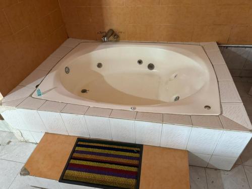 a white bath tub in a bathroom with a tile floor at Hotel Acambay in Acambay