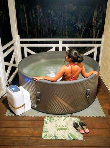 a woman sitting in a bath tub on a deck at EVASION Bungalow Tropical Spa in Sarraméa