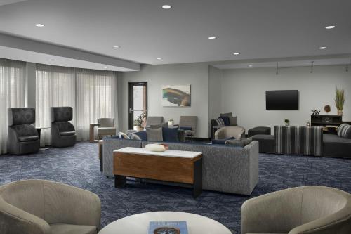 a living room with couches and chairs and a tv at Courtyard Greensboro Airport in Greensboro
