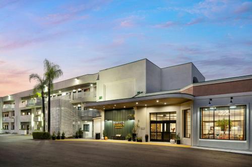 a large white building with a palm tree in front of it at Tiller House, Laguna Hills, a Tribute Portfolio Hotel in Laguna Hills