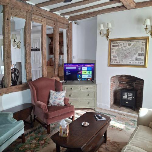 a living room with a tv and a chair and a table at The Abbey Hotel & Apartments in Bury Saint Edmunds