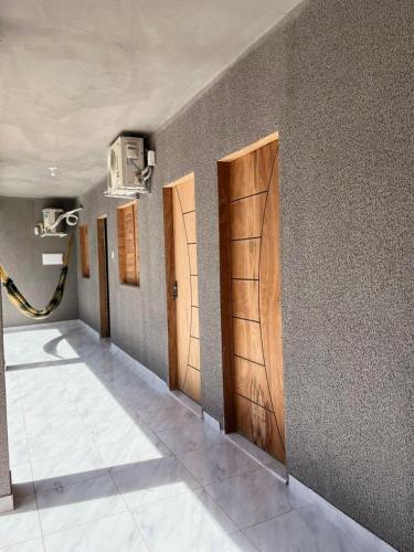 a hallway with two wooden doors and a tile floor at Pousada encantos de morro branco in Beberibe