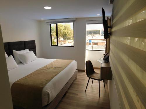 a bedroom with a bed and a desk and a window at HOTEL MX BOGOTA in Bogotá