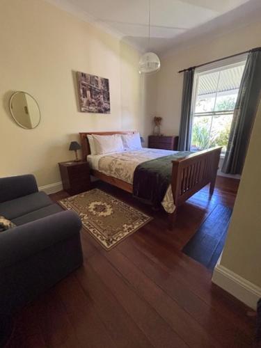 a bedroom with a bed and a couch and a window at Halfmoon Cottage in Akaroa
