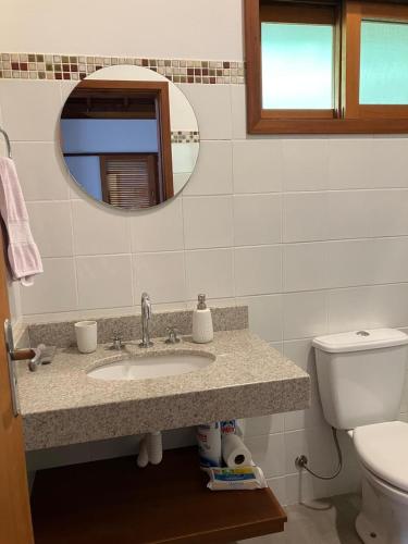 a bathroom with a sink and a toilet and a mirror at Chalé das Flores - Refúgio com clima de chácara no Centro de Gonçalves in Gonçalves