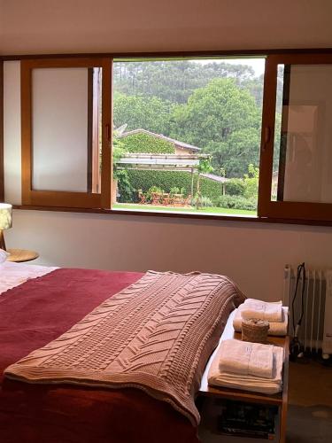 a bedroom with a bed with a large window at Chalé das Flores - Refúgio com clima de chácara no Centro de Gonçalves in Gonçalves