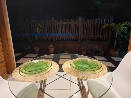 a glass table with two green plates on top of it at Gwada fun habitation in Saint-Claude