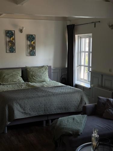 a bedroom with a bed and a window and a couch at B&B D'n Optie in Druten