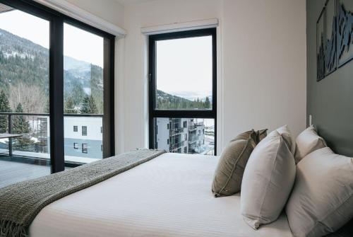 a bedroom with a large bed with large windows at Cloudscape Penthouse by Revelstoke Vacations in Revelstoke