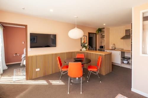 a kitchen and dining room with a table and orange chairs at Studio C with all you need in Wanaka