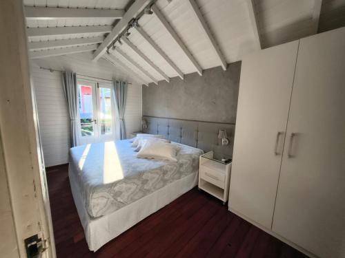 a bedroom with a white bed and a white cabinet at Casa para temporada in Florianópolis