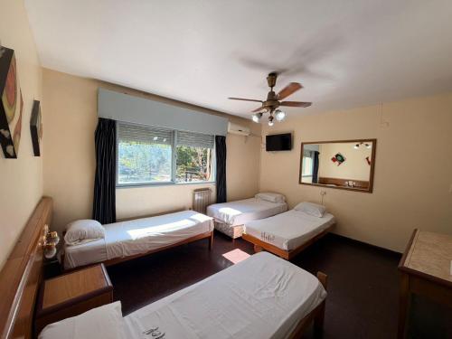a room with three beds and a ceiling fan at Hotel Aldeano ll in Buenos Aires