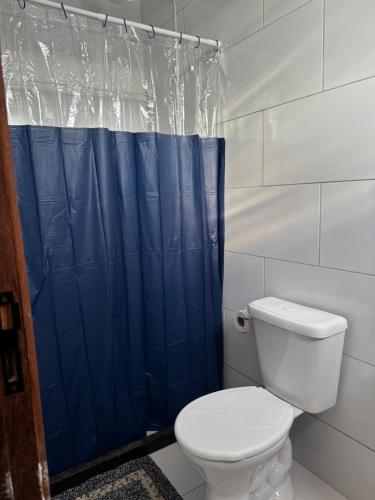 a bathroom with a toilet and a blue shower curtain at El Laai Roi in Iguaba Grande