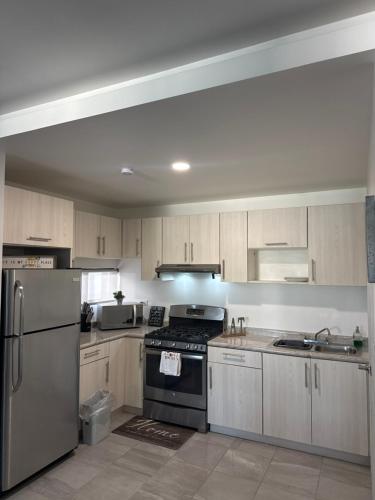 a kitchen with wooden cabinets and a stove top oven at Depa en La Cienega in Tijuana