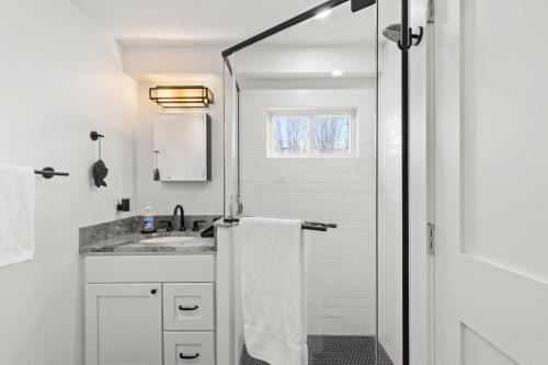 a white bathroom with a sink and a shower at West End Haven w/ Modern Kitchen + Private Yard in Provincetown