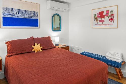 a bedroom with a red bed with a orange comforter at West End Haven w/ Modern Kitchen + Private Yard in Provincetown