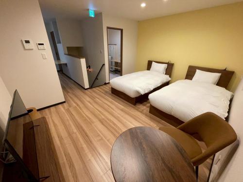 a hotel room with two beds and a table at Casa Kokoro Hakuba in Hakuba