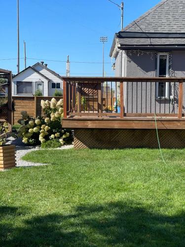 a wooden deck on a house with green grass at Friendship Residence in Thunder Bay
