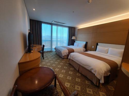 a hotel room with two beds and a desk and a television at Sun Valley Hotel in Yeoju