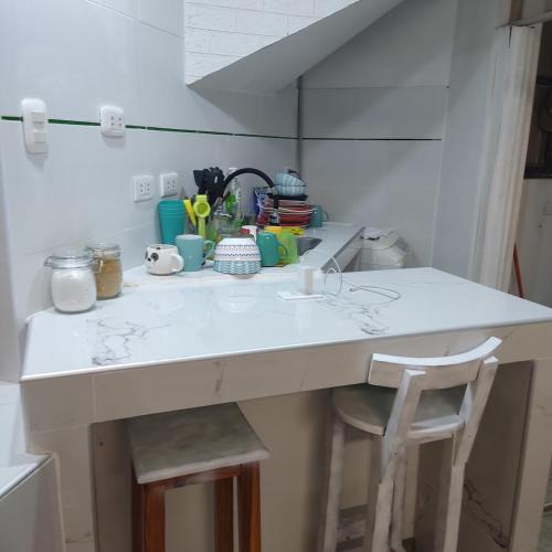 a kitchen counter with two stools and a sink at La Palmera Apartment in San Bartolo