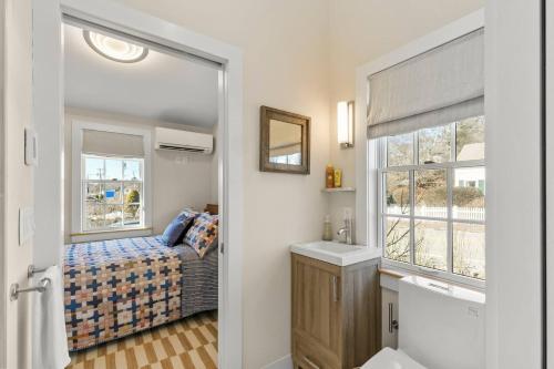 a bathroom with a bed and a sink and a mirror at Modern Design - Walk to Galleries + Beach + Dining in Provincetown