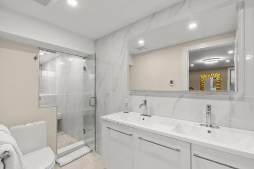 a white bathroom with a sink and a shower at Modern Design - Walk to Galleries + Beach + Dining in Provincetown