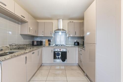 a kitchen with white cabinets and a washer and dryer at Spacious 4-Bed Home Near Cribbs & Bristol in Bristol